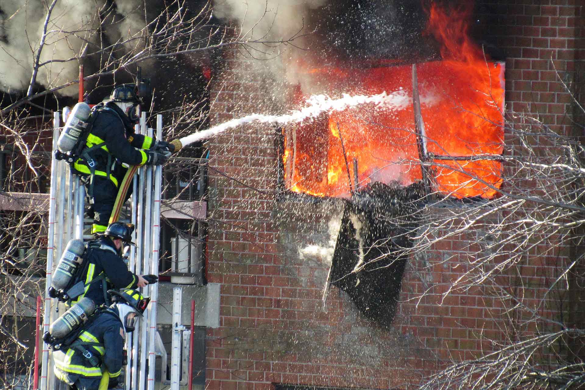 Firefighter Sprays Water on Burning House